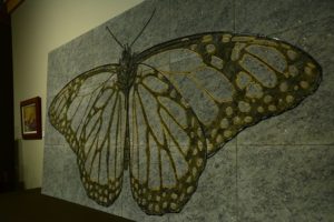 Monarch butterfly engraved on green granite and painted black and gold.
