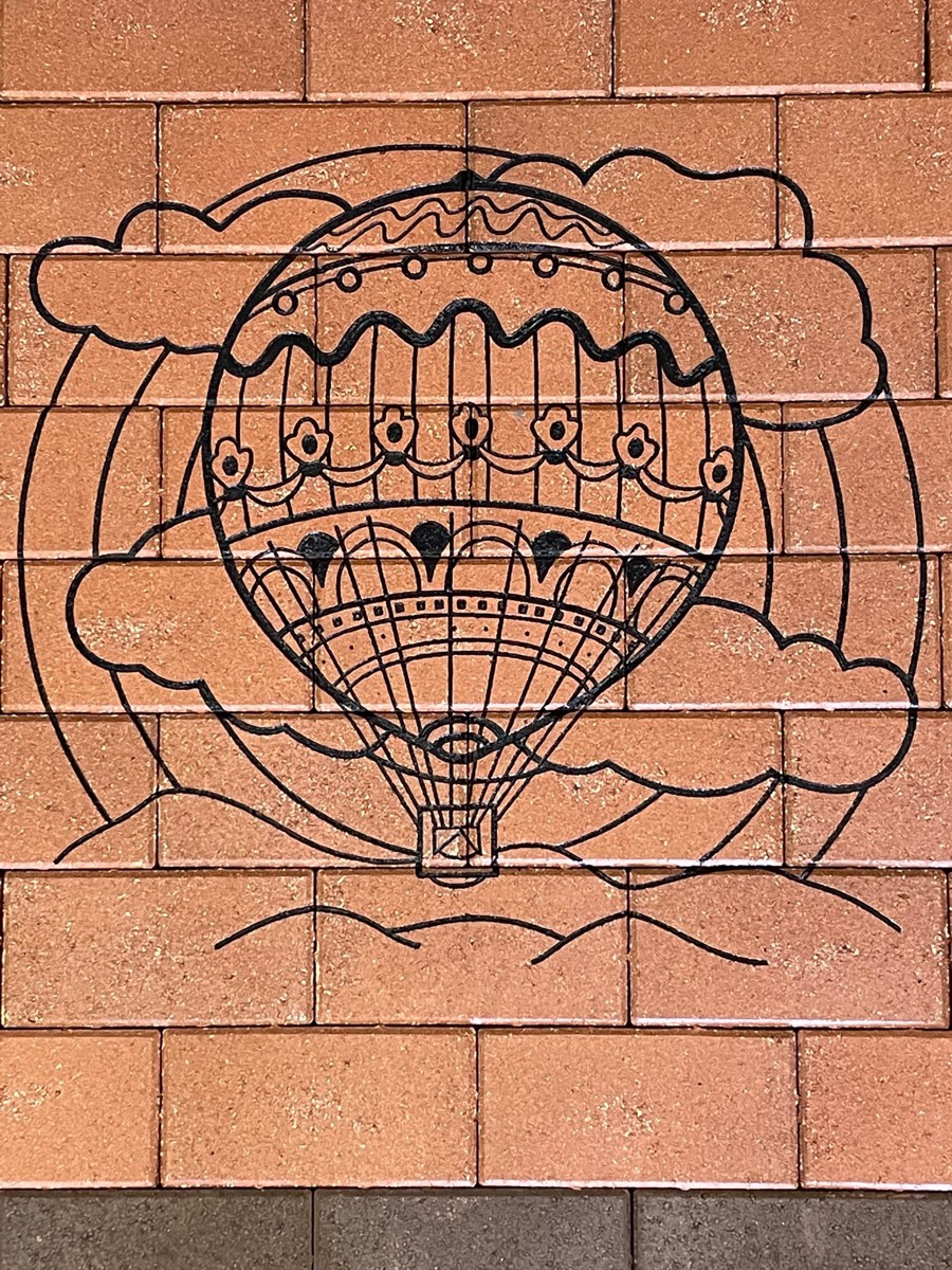 Stylized hot air balloon engraved on clay pavers and hand painted black.