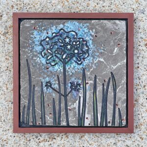 Marble tile with a dandilion engraved and painted blue on it.