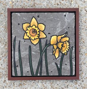 marble tile with daffodils engraved and painted on it