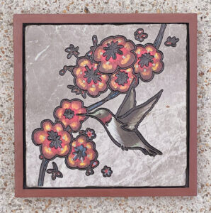 Marble tile with a hummingbird and flowers on a vine engraved and painted on it.