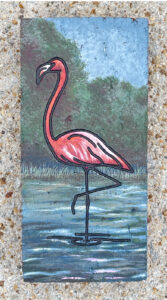 Clay paver with pink flamingo standing in water engraved and painted on it.
