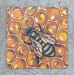 Limestone tile with a bee tending a honeycomb engraved and painted on it.