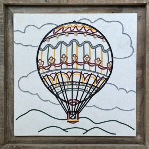 Limestone tile with a hot air balloon floating in the clouds engraved and painted on it.