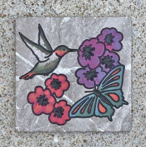 Marble tile with a hummingbird, butterfly, and flowers engraved and painted on it.
