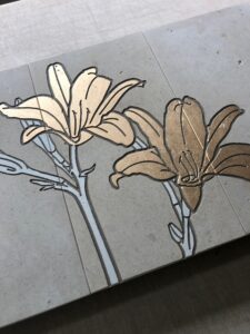 Three limestone plaques engraved with two lilies engraved and painted gold on them.