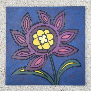 Granite tile with a stylized flower engraved and painted on it.