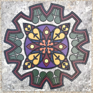Travertine tile with a stained glass designed engraved and painted on it.