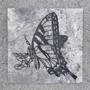 Travertine tile with a swallowtail butterfly and flowers engraved and painted on it.