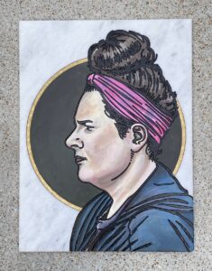 Marble tile with woman in profile engraved and painted on it.