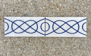 4in. x 8in. engraved white marble tiles aligned in a pattern White marble tiles with identical design placed side by side to display a pattern
