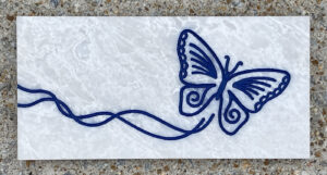 4in. x 8in. engraved white marble tile, blue lacquer White marble tile with a butterfly design engraved and painted in blue on it.