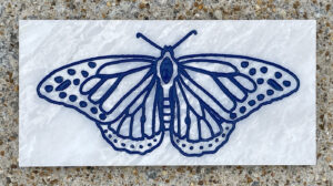 4in. x 8in. engraved white marble tile, blue lacquer White marble tile with a butterfly design engraved and painted in blue on it.